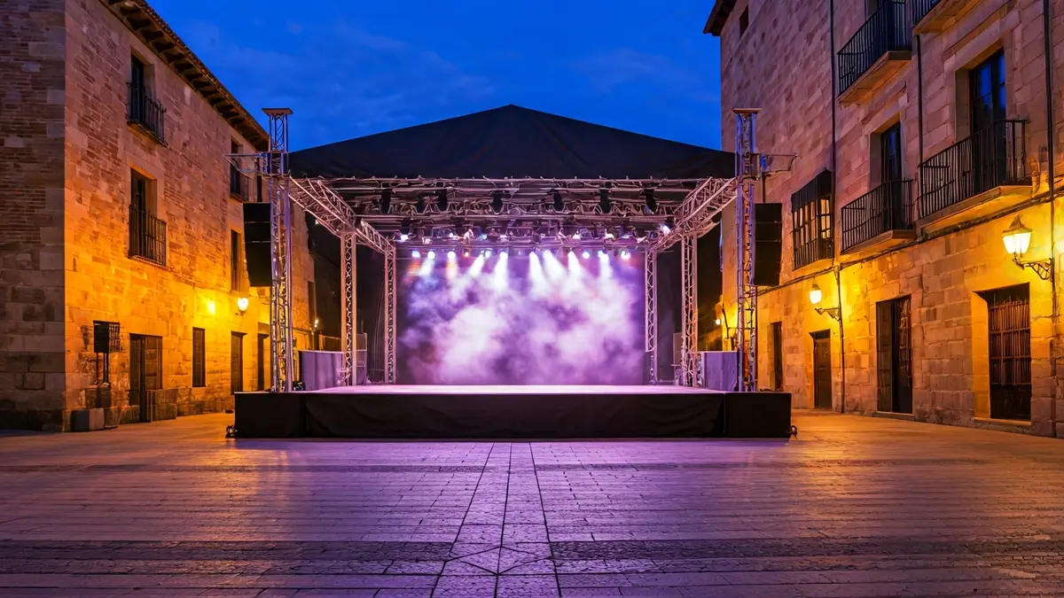 Escenario al aire libre en una plaza histórica de Alcalá de Henares, preparado para un festival cultural.