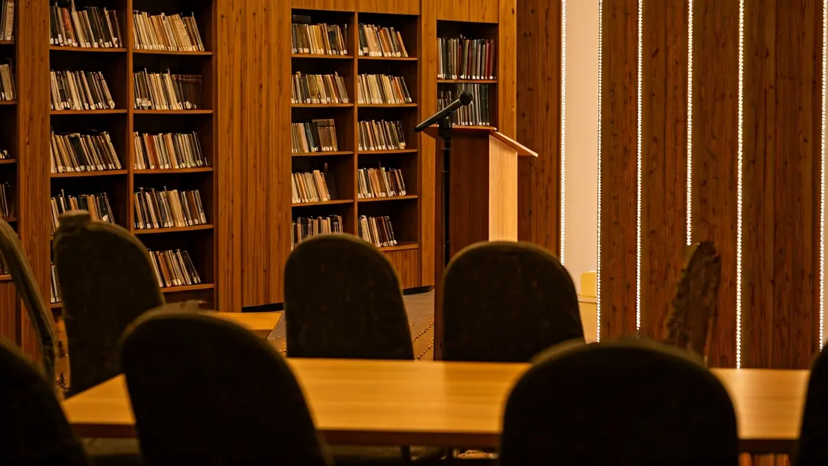 Generic image of a cultural space with bookshelves and a podium.