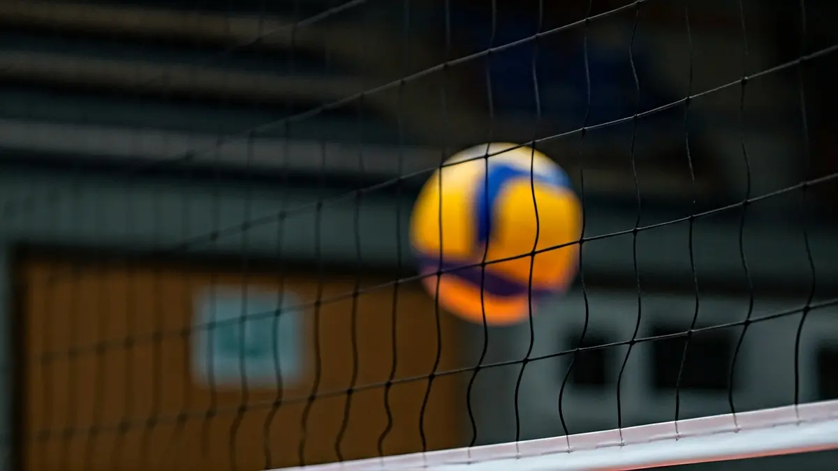 Imagen genérica de una red de voleibol con un balón en el aire.