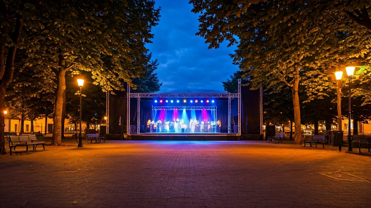 Generic image of an outdoor stage in a park at dusk, with colorful lights.