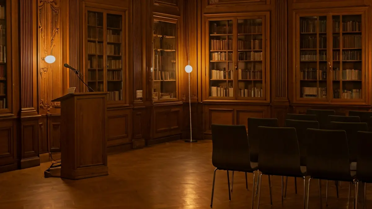 Generic image of a library interior with a podium and chairs, evoking a literary gathering.