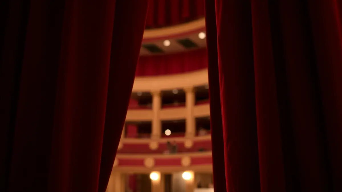 Generic image of a red opera curtain, slightly open, with a blurred theater interior in the background.