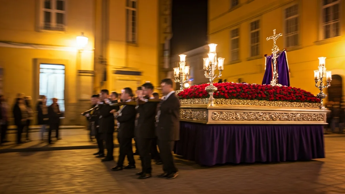 Imagen de una procesión de Semana Santa en una calle histórica de Madrid al anochecer.