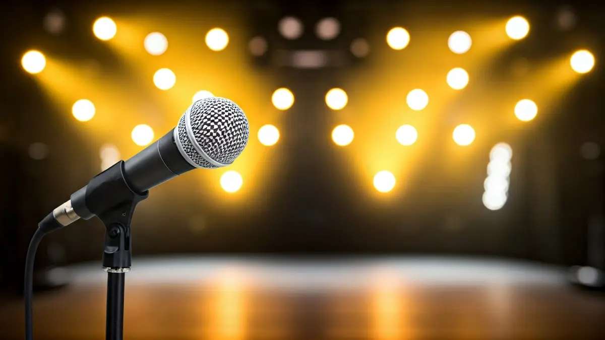 Generic image of a microphone on a stage, with blurred concert lights in the background.