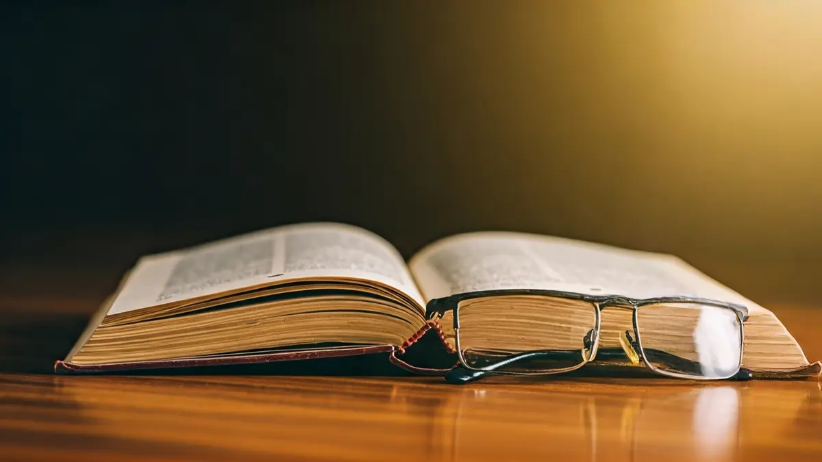 Generic image of an open law book on a wooden table with reading glasses.