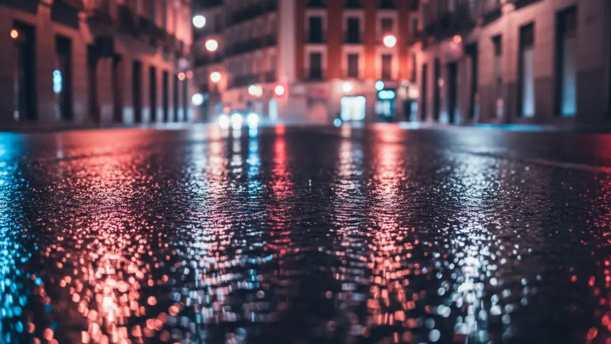 Imagen genérica de luces de emergencia reflejadas en el asfalto mojado en un entorno urbano de Madrid.