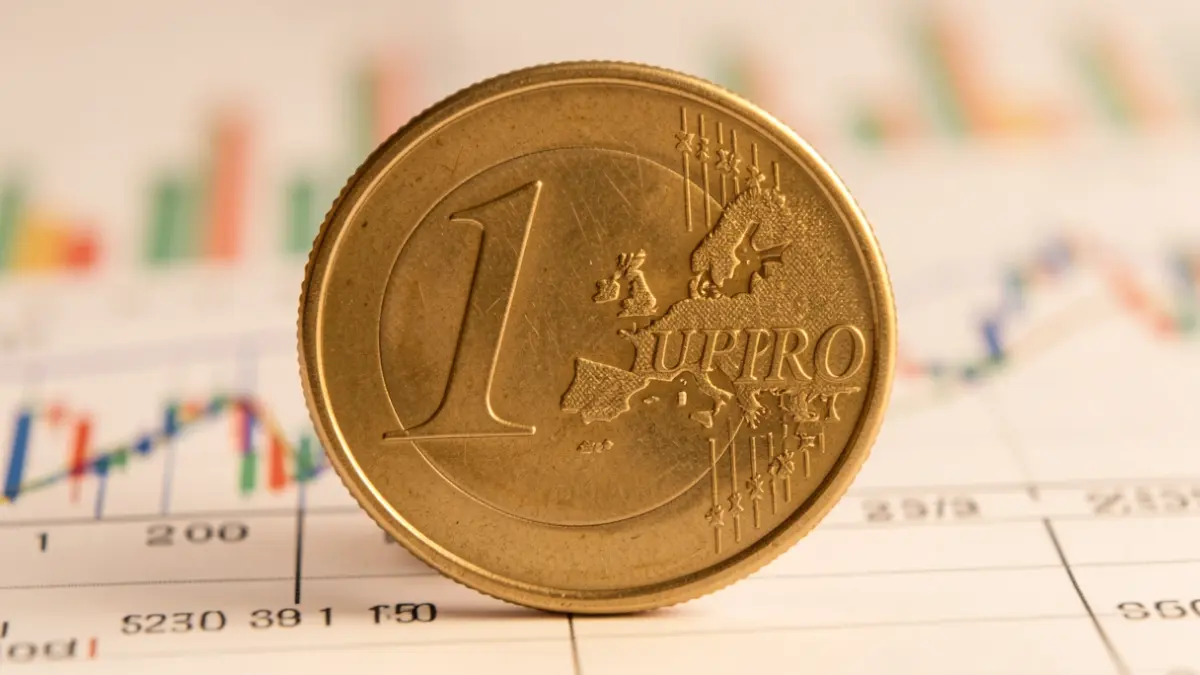 Primer plano de una moneda de euro con una flecha ascendente sobre gráficos financieros.