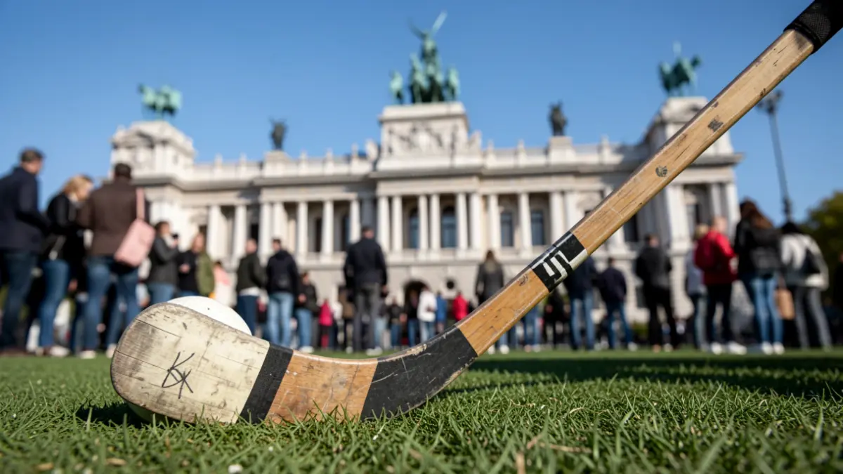 Primer plano de un stick y una pelota de hockey sobre hierba en un campo, con el Palacio de Cibeles desenfocado al fondo.