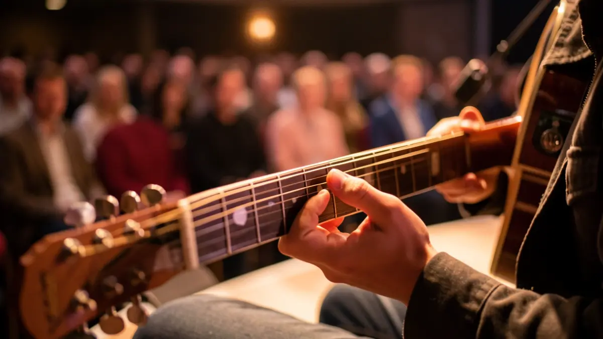 Close-up of a young person's hands playing a guitar on a stage with warm lighting.