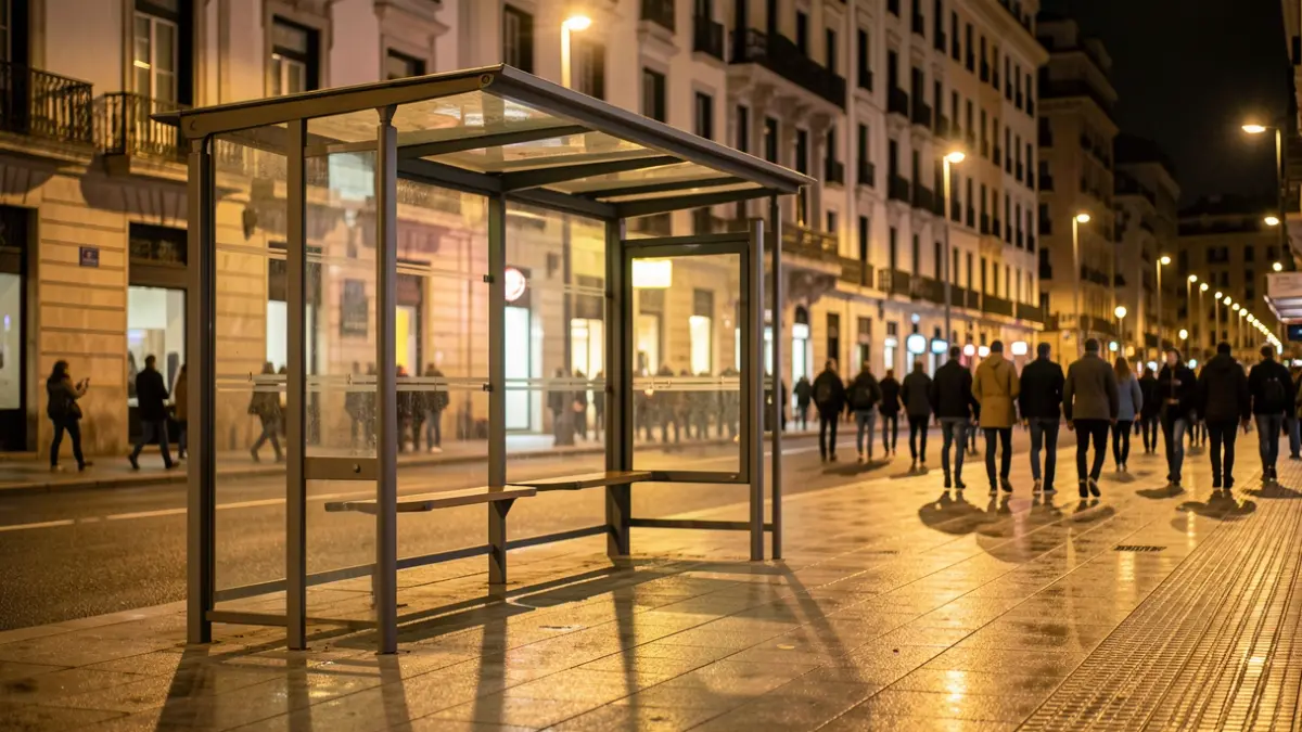 Parada de autobús vacía por la noche en Madrid con luces cálidas.