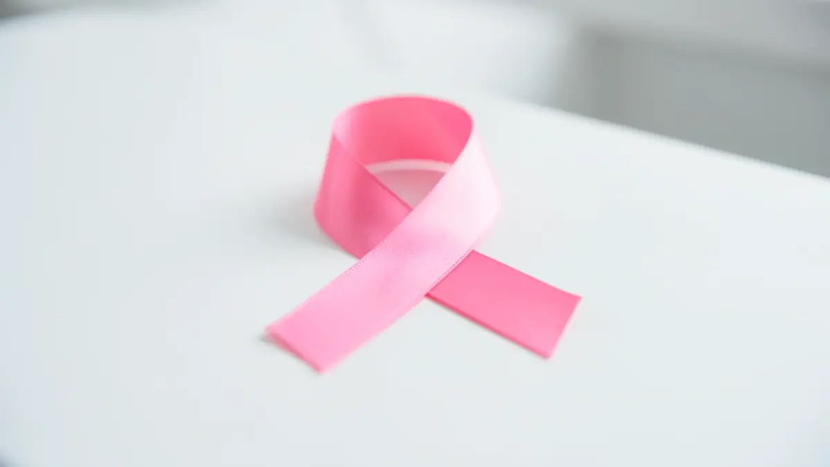 Generic image of a pink ribbon for breast cancer awareness on a white medical surface.